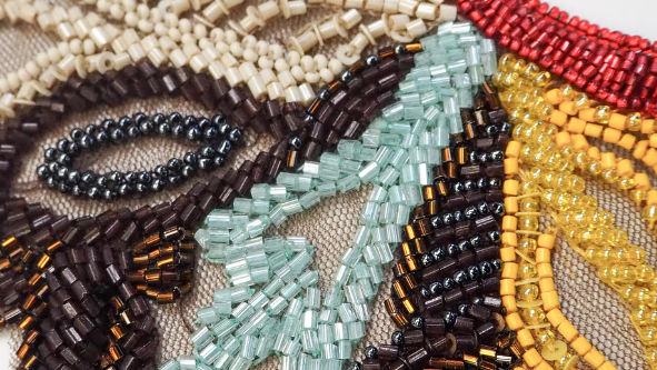Close-up of an intricately beaded and embroidered necklace with a white background